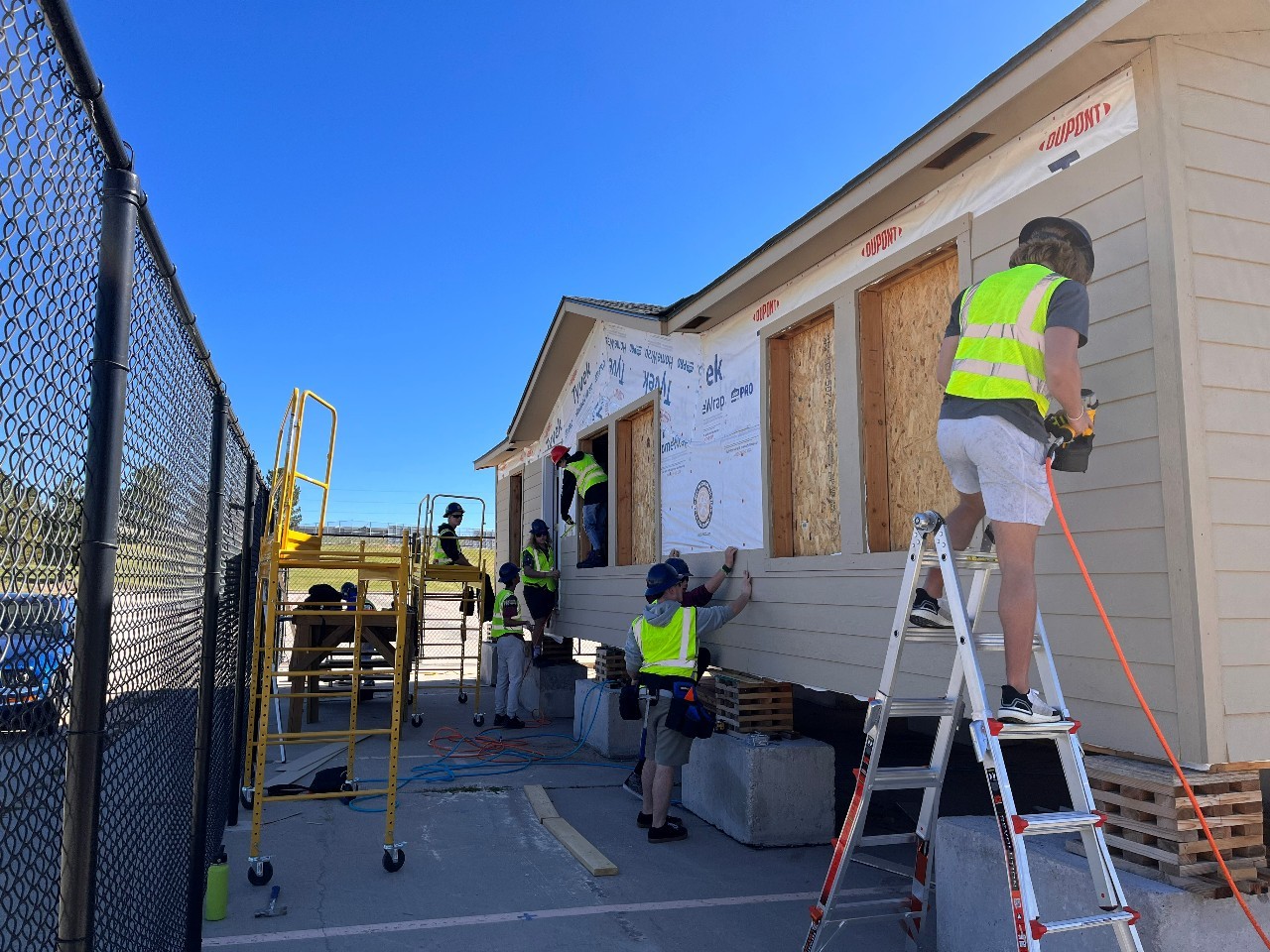 Students work on the exterior of a house.